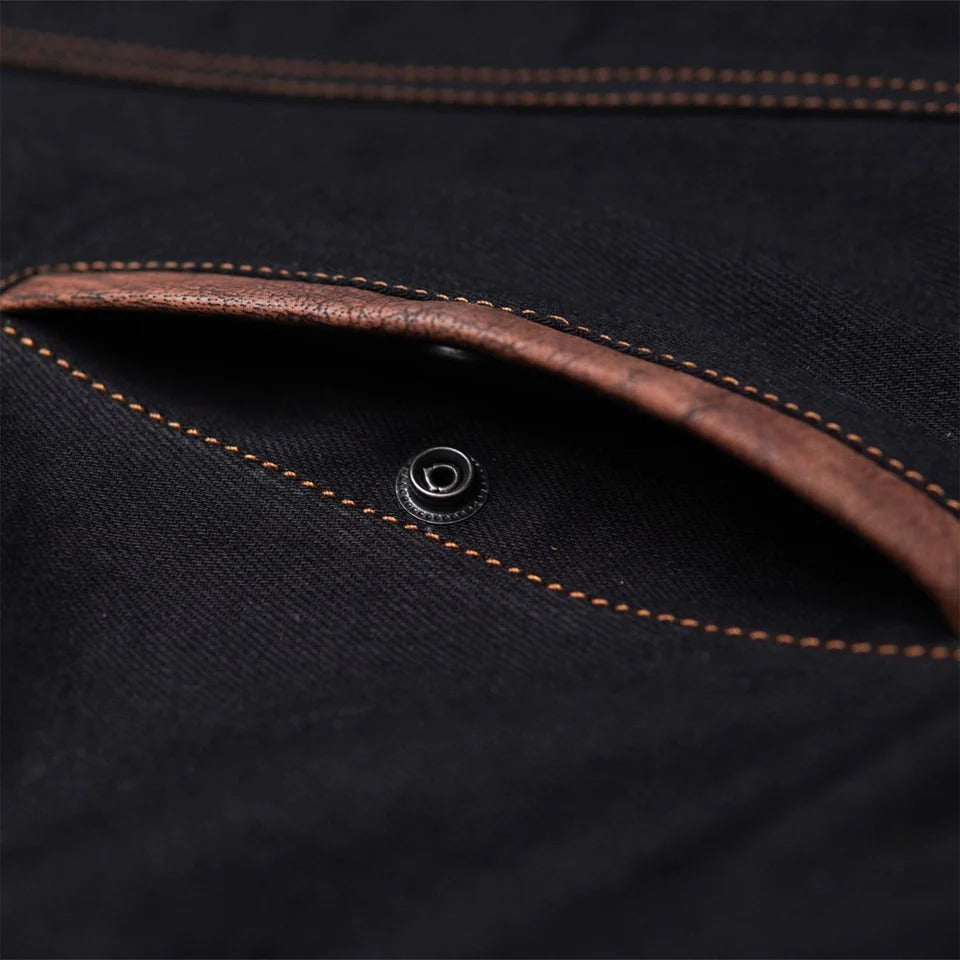 Close-up of black fabric with brown stitching and button