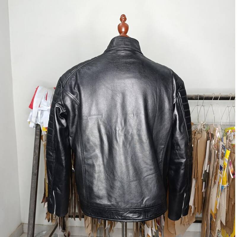 Black leather jacket on a mannequin against a clothing rack background